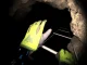 Player wearing VR headset navigating a realistic virtual cave environment with flashlight and tools.
